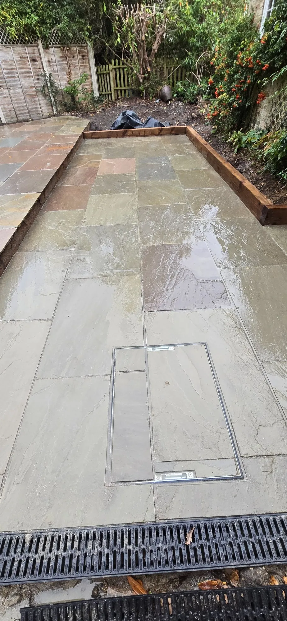Recessed inspection cover infilled with matching sandstone beside new linear drainage