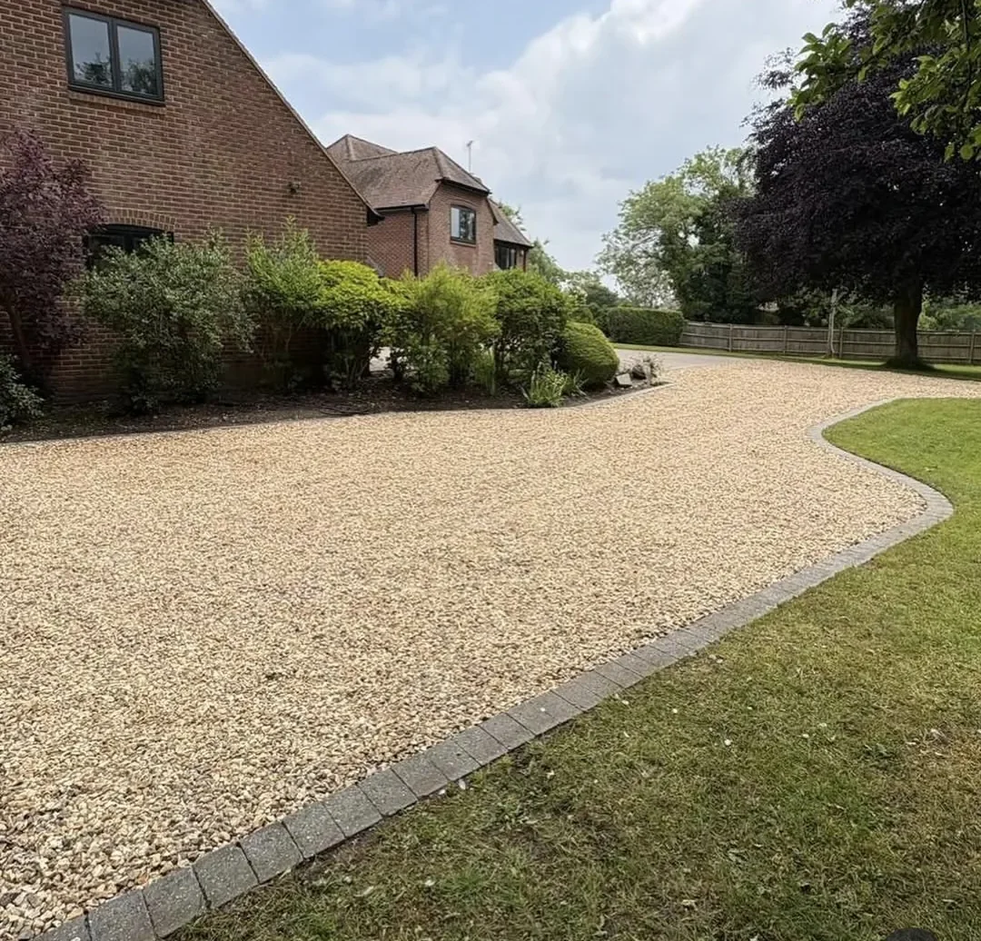 Gravel driveway with block-paved edging curving past a brick house in Surrey
