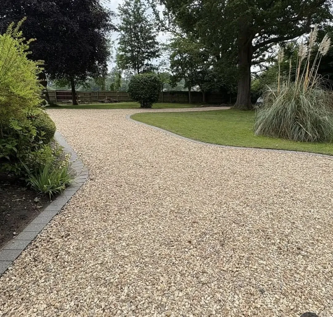 Wide gravel driveway with block-paved edging and mature trees in a Surrey country garden