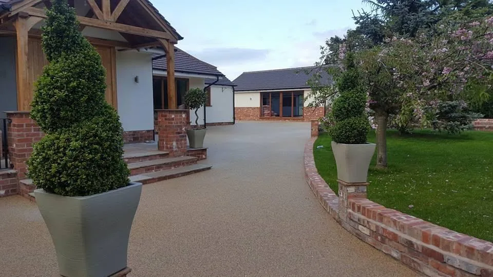 Resin bound driveway with brick edging and steps leading to a house in Surrey