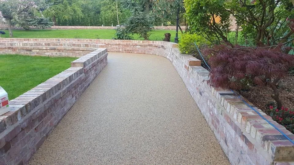 Sweeping resin driveway with a curved brick retaining wall on a rural Surrey property