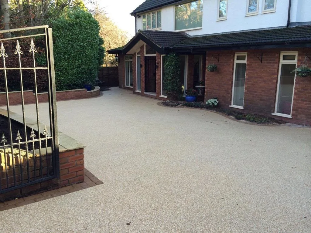 Wide resin driveway with wrought-iron gates in front of a large Surrey home