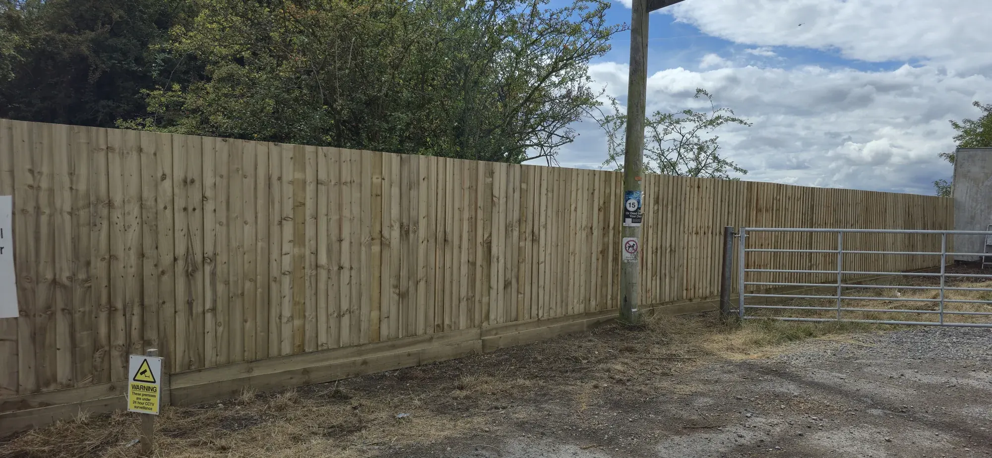 Long run of tall close-board timber fencing along a yard boundary in Surrey