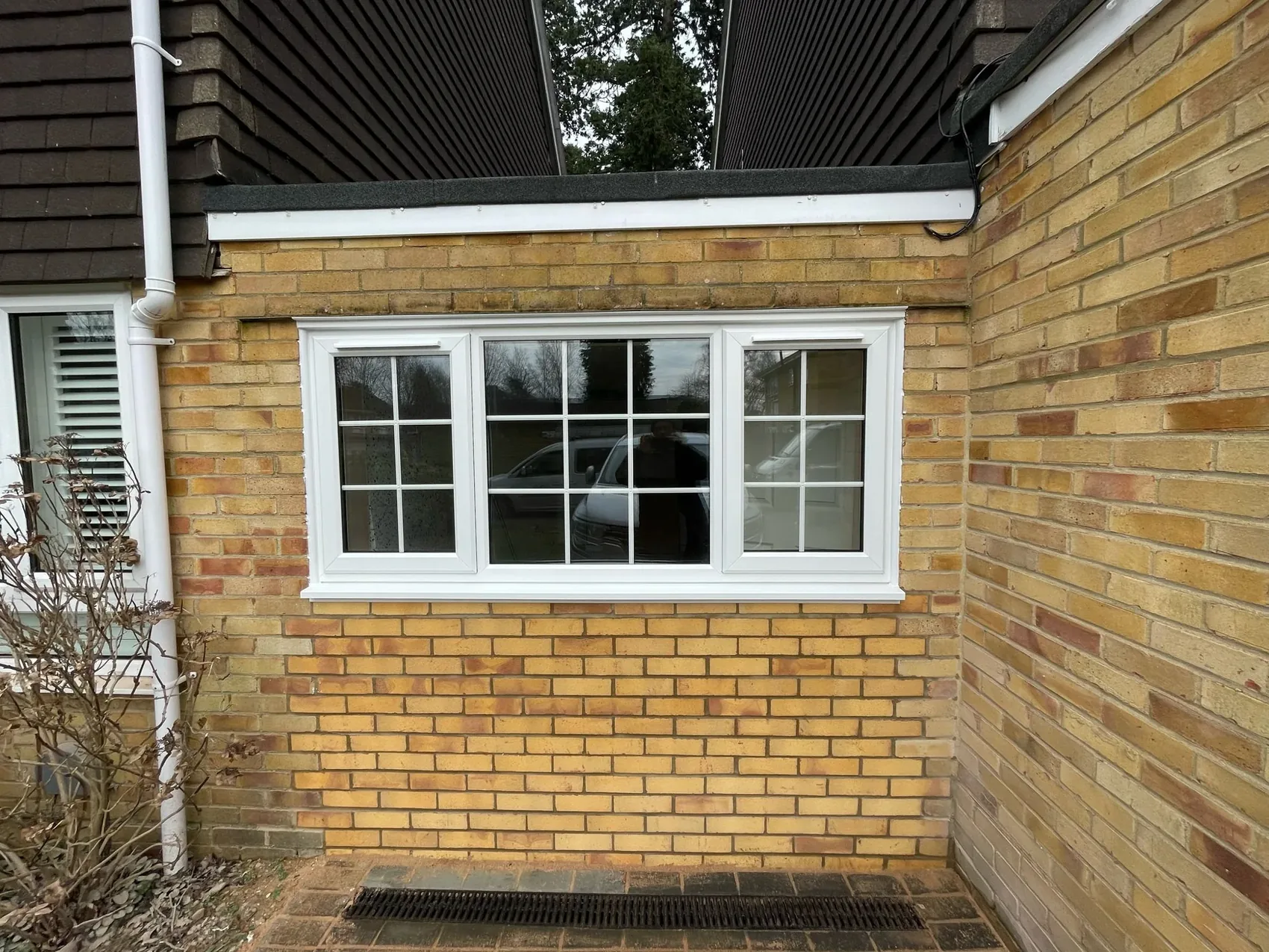 Former garage opening bricked up with a new white uPVC window during a garage conversion