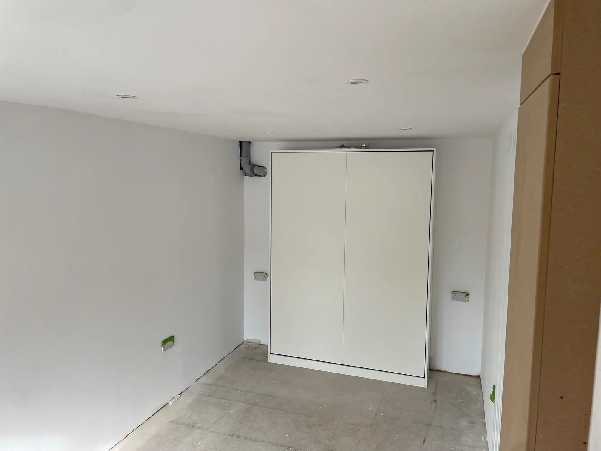 Finished garage conversion with fitted storage cupboards and fresh plaster in Surrey