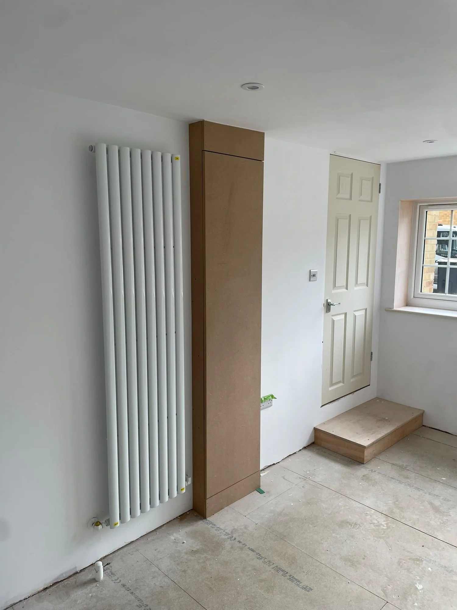 Finished garage conversion with a vertical designer radiator, internal door and window in Surrey