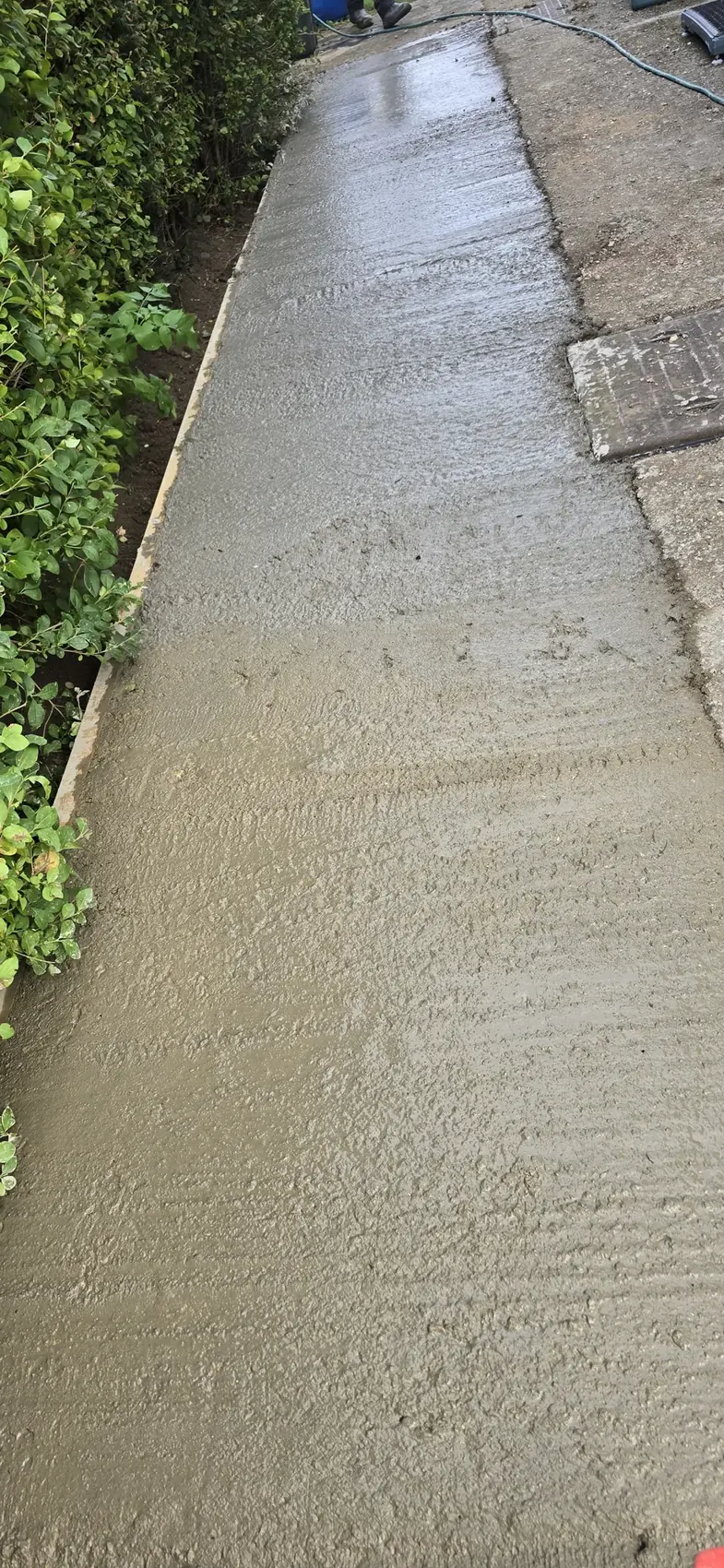 Freshly poured concrete slab being finished against timber formwork on a groundworks project