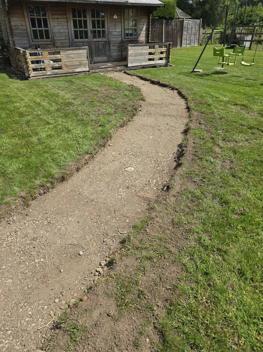 Excavated pathway line dug and levelled across a garden lawn during groundworks