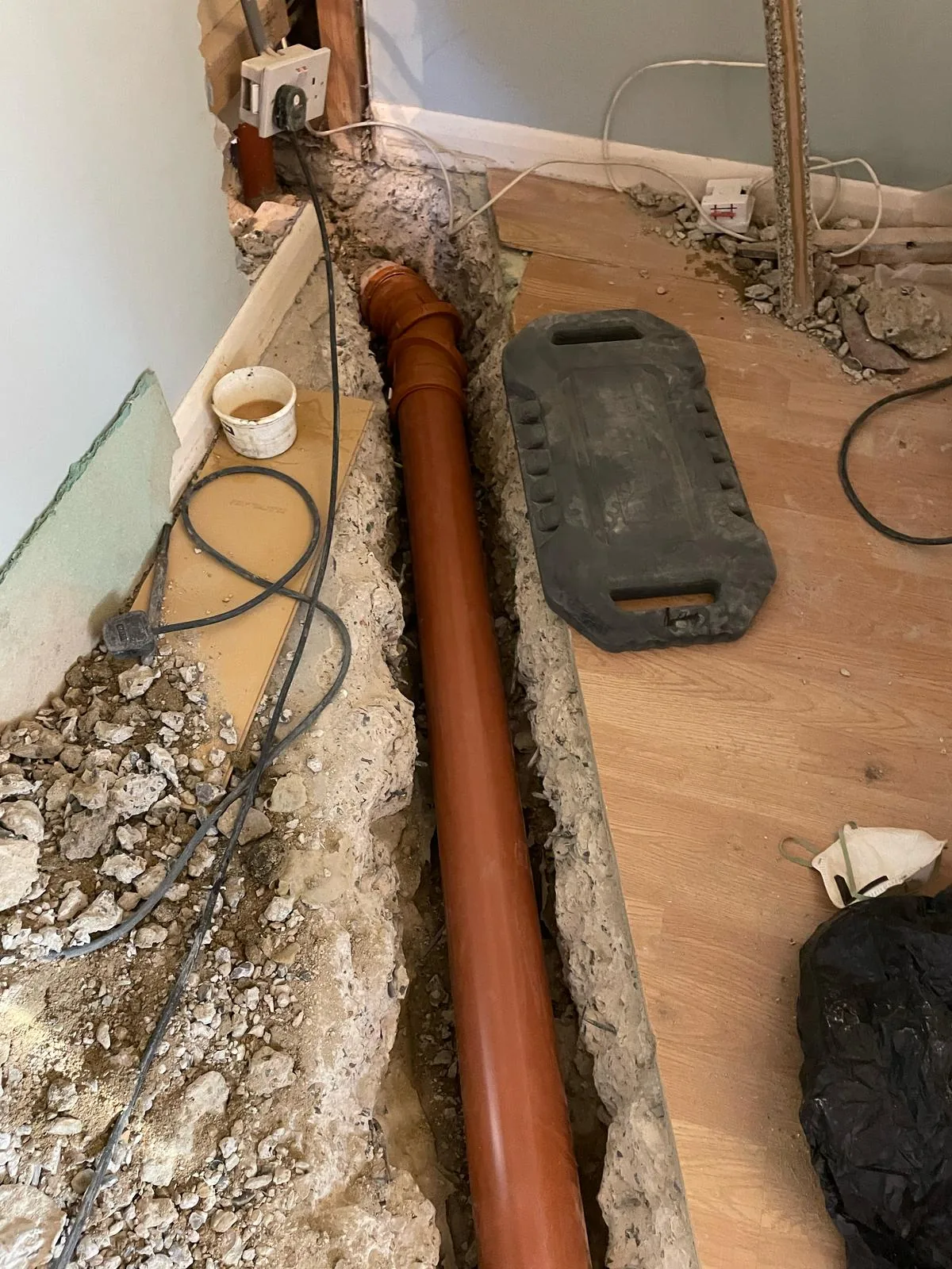 New underground drainage soil pipe laid in a channel cut through a concrete floor