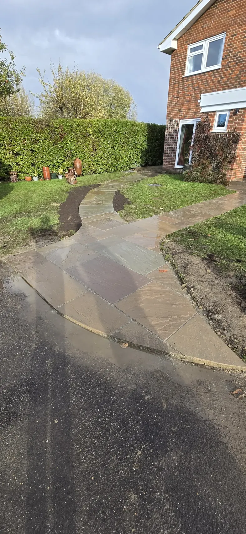 Indian sandstone front path bordered by hedging leading to a house in Surrey