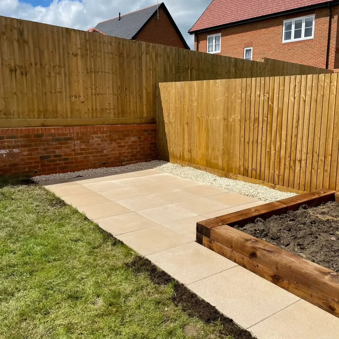Buff slab patio with gravel border and timber sleeper bed in a new-build Surrey garden