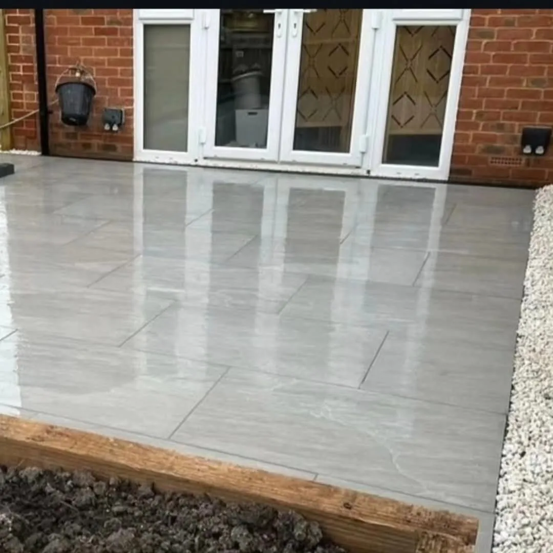 Grey riven porcelain patio outside French doors with a gravel border in a Surrey garden