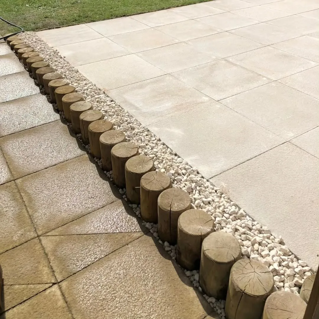 Buff slab patio with a white gravel channel and timber log post edging in a Surrey garden